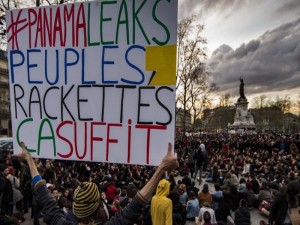 epa05244050 A man holds a sign which reads '#Panama Leaks, People, Racketeering, it's enough' as demonstrators gather for a general assembly sit-in as part of the 'La Nuit Debout' (The Night Up) movement which has reached its fourth night, on Place de la Republique, to protest against the labor law reform bill in Paris, France, 04 April 2016. French students and labor unions have taken to the streets throughout the month of March to protest against a draft of a labor reform law led by French Labor Minister Myriam El Khomri.  EPA/IAN LANGSDON