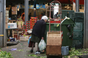 Poveri a Roma nel mercato rionale di Val Melaina raccolgono generi di prima necessità in terra tra gli scarti, un una foto d'archivio. Secondo l'Istat, un italiano su tre e' a rischio poverta', il 50% al sud. Roma, 16 dicembre 2013.  ANSA/MASSIMO PERCOSSI / SIM